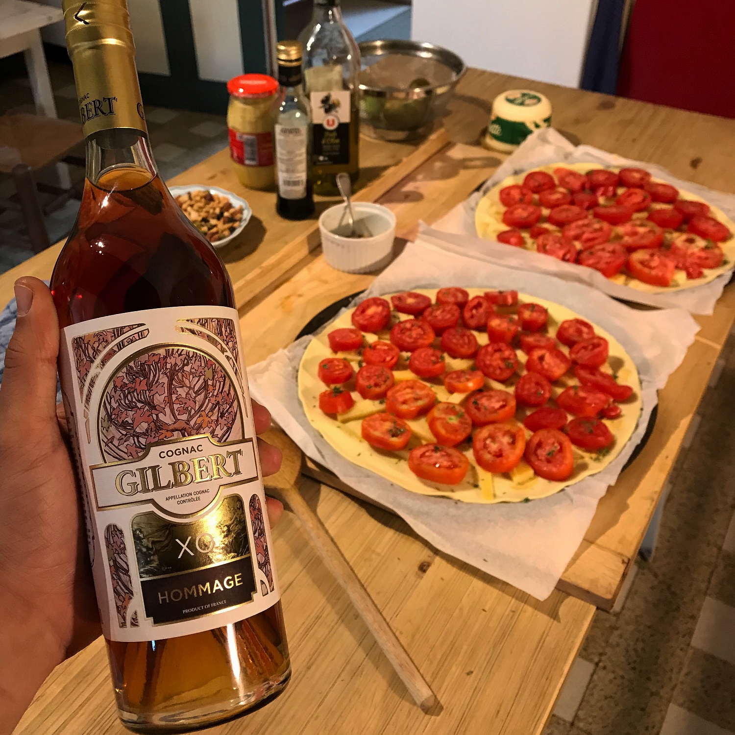 A bottle of Gilbert XO with Pizzas in the background