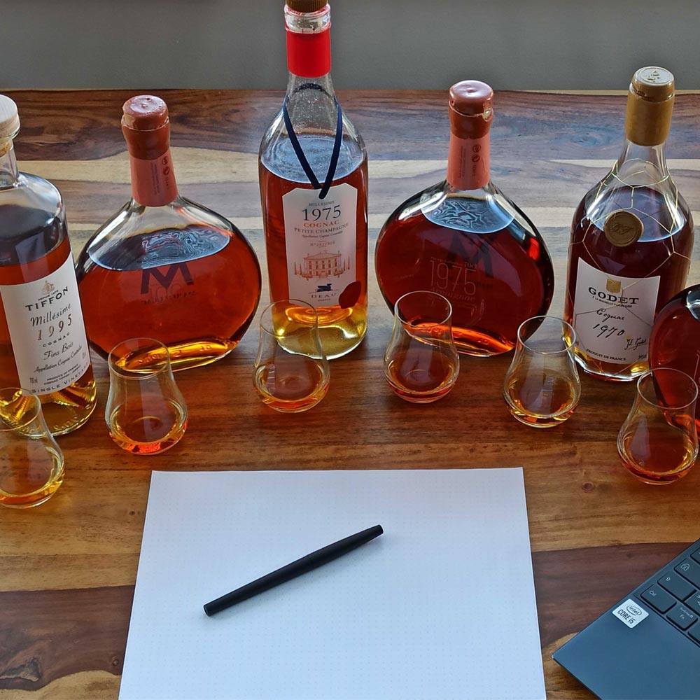 3 Cognac bottles and 3 Armagnac bottles aligned in a half circle in front of filled glases